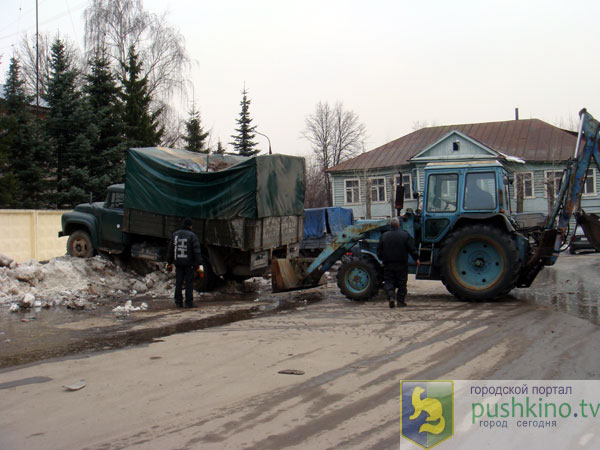 Трактор заталкивает грузовик в сугроб